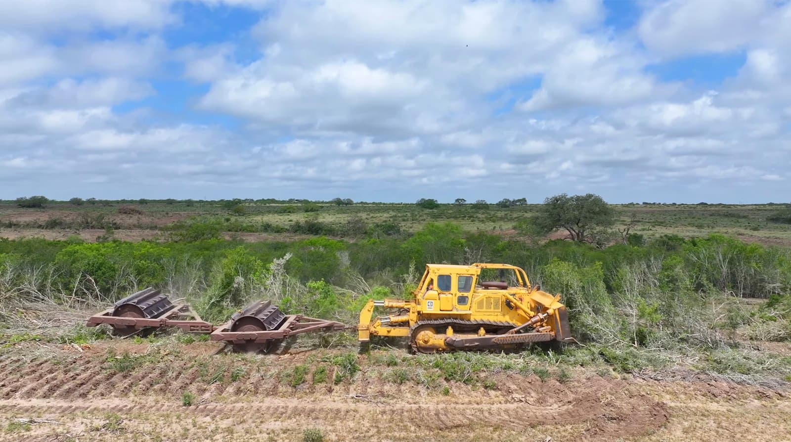 Cat D9H pulling the 20ft double drum roller chopper through South Texas brush