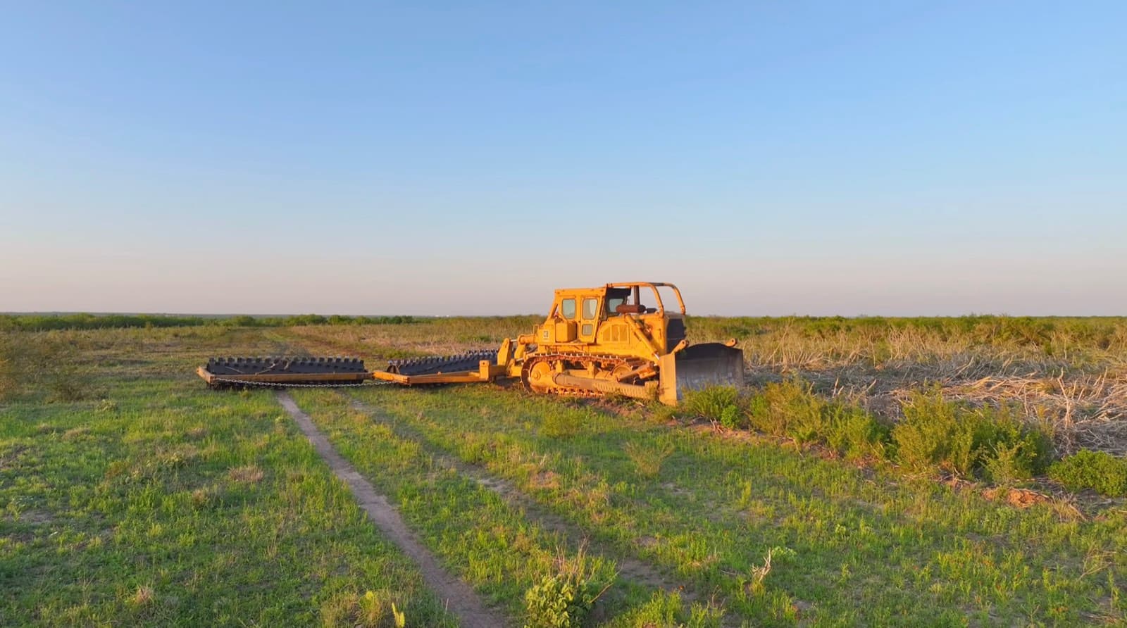 Aerial view of Cat D9H pulling the 54-foot roller chopper across South Texas land